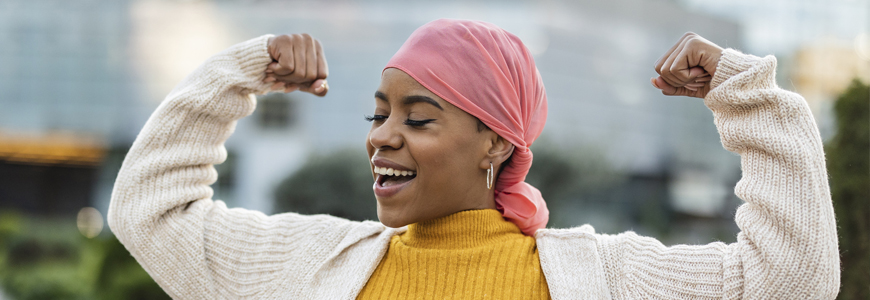 A young black woman with cancer flexing her muscles in celebration