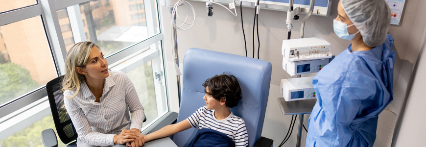 Boy holding hands with his mother while getting his chemotherapy at the hospital
