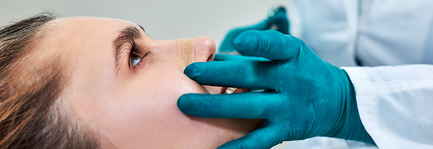 physician examing nose of female patient post surgery