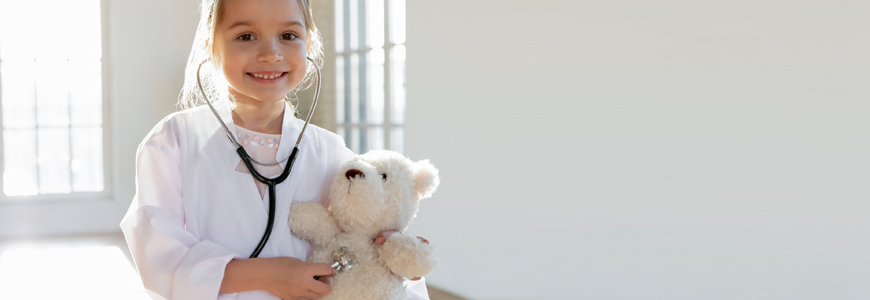 Little girl playing doctor with her teddy bear