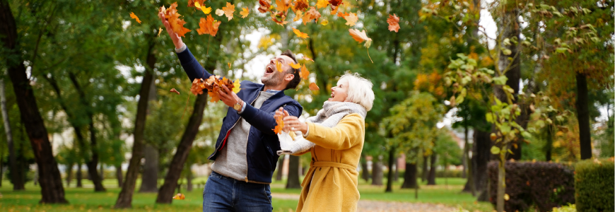 Couple having fun together outdoor in the golden autumn park, throwing leaves and laughing.