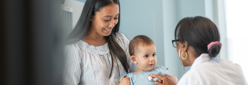 Female pediatrician checks heart of baby girl in medical appointment