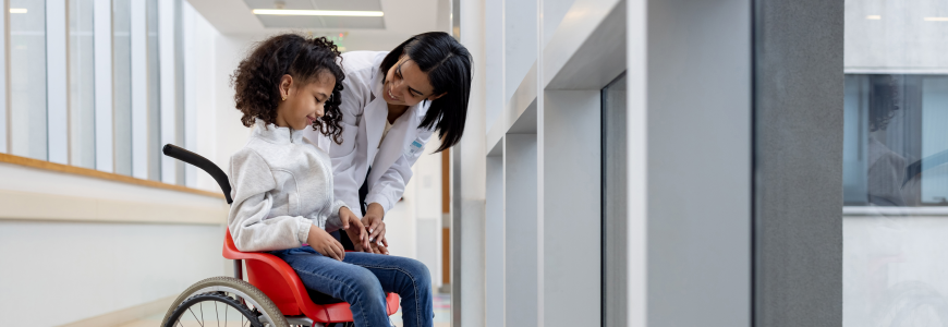 Doctor talking to a girl with cerebral palsy in a wheelchair at the hospital