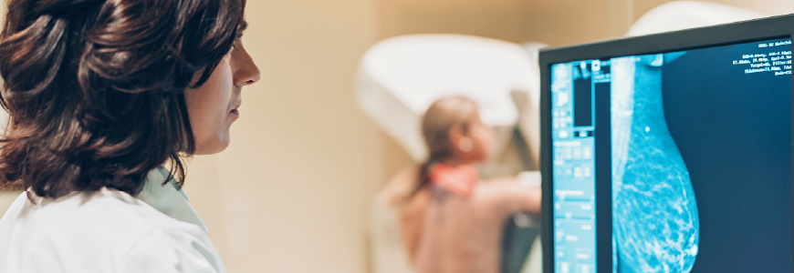 A patient getting a mammogram with the technician in the forefront