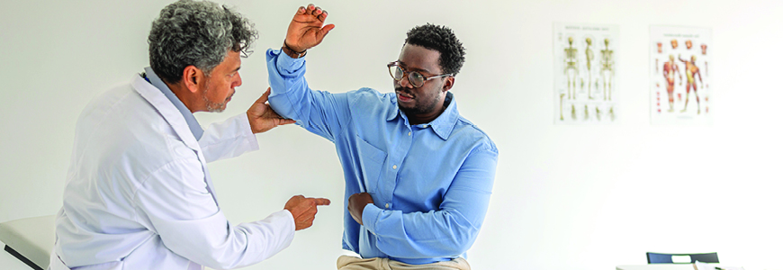 Doctor examines a male patient's shoulder and arm during a clinical consultation