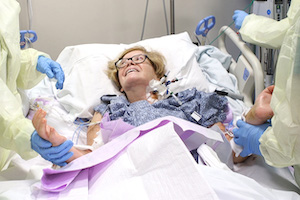 Woman has bandages changed by two physicians. 