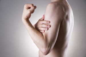 Man with pain in arm. Pain in the human body on a gray background