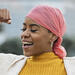 A young black woman with cancer flexing her muscles in celebration