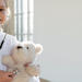 Little girl playing doctor with her teddy bear