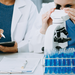 Physician researchers in lab with one looking in a microscope