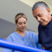 Latin American man doing physical therapy and walking on bars with the assistance of his physical therapist